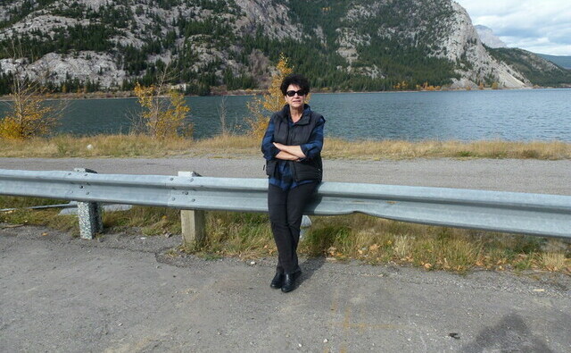 Dr. M Anne Naeth leaning against a roadside highway barrier