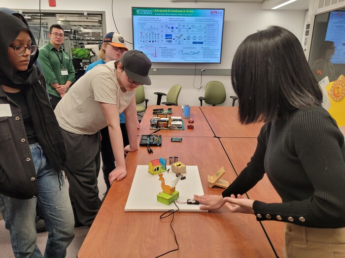 Postdoctoral fellow Xiaoting Wang, PhD (right), demonstrates the benefits of energy storage in stabilizing the grid. Inside Dr. Ryan Li’s lab, students explored the demands on our energy grid imposed by charging electric vehicles, the use of artificial intelligence (AI), and more. 